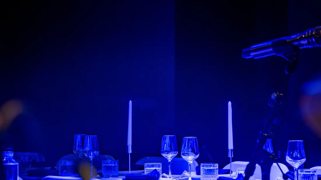 A dinner table set in the Live Room under blue stage light