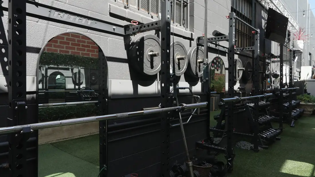 Squat racks and plates along the outdoor gym wall